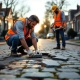 Huiseigenaar onderzoekt losse klinkers terwijl aannemer met hamer advies geeft op Nederlandse straat