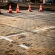 Nieuw aangelegd commercieel parkeerterrein met betonklinkers, rijbaanmarkeringen en oranje veiligheidskegels in Nederlands middaglicht.