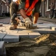 Vakman in oranje veiligheidsvest legt grijze betonklinkers op een Nederlandse straat en tikt ze vast met een rubberen hamer.